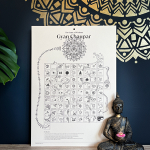 Gyan Chaupar game board with golden mandala on wall behind and a small Buddha sitting in the foreground