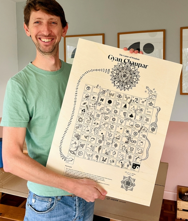 Tom holding a plywood version of the game gyan chaupar